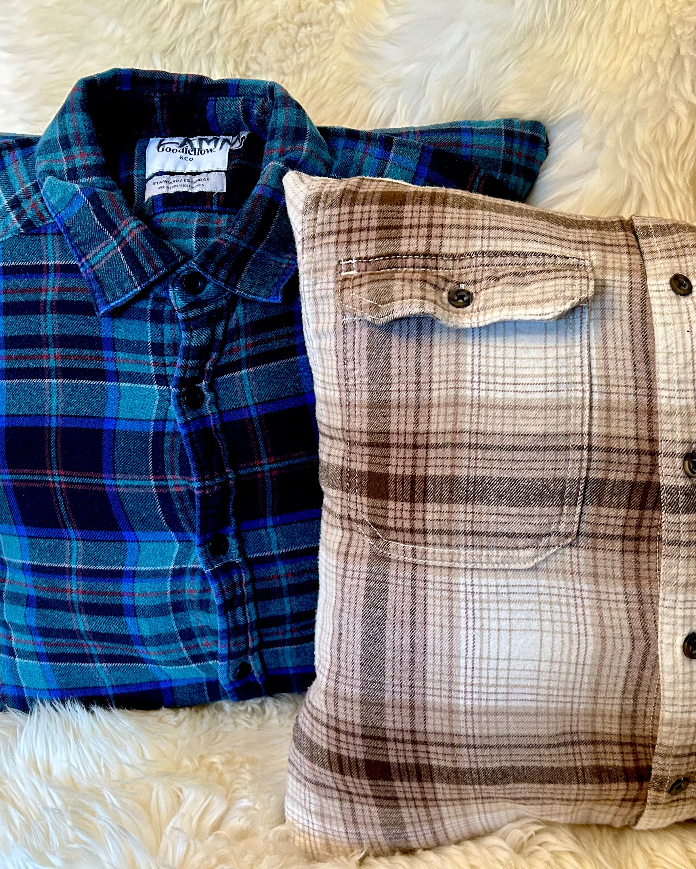 Two plaid pillows, one blue and one brown, on a fluffy white surface.