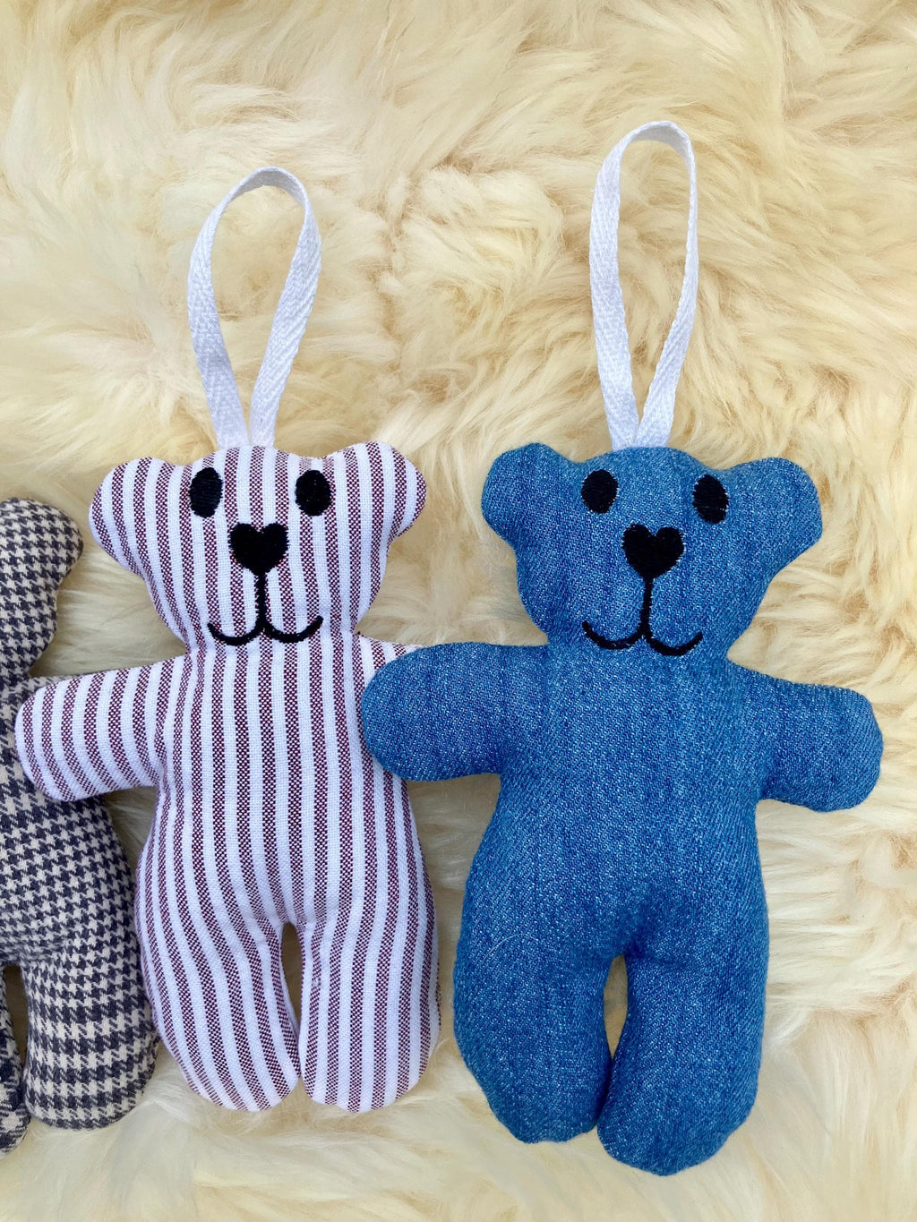 Two small teddy bear toys with ribbons on a textured beige surface